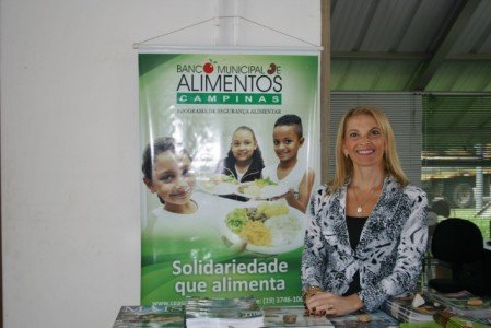 Alexandra Capriolli mostra banner do Banco de Alimentos