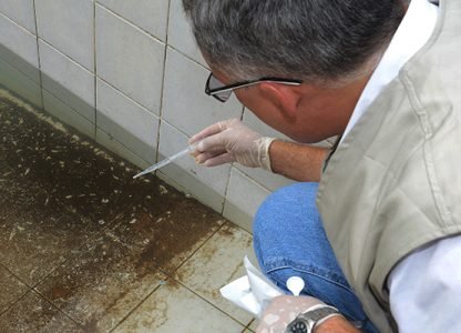 Técnico retira amostra de água da piscina para análise