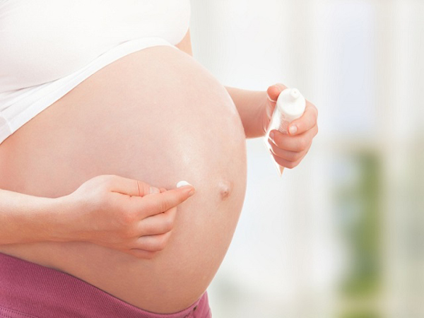 belly of pregnant woman and moisturizing cream