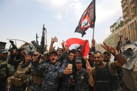 Members of the Iraqi federal police dance and wave their country's national flag in celebration in the Old City of Mosul on July 8, 2017, as their part of the battle has been declared accomplished, while other forces continue to fight Islamic State (IS) jihadists in the city. / AFP PHOTO / AHMAD AL-RUBAYE